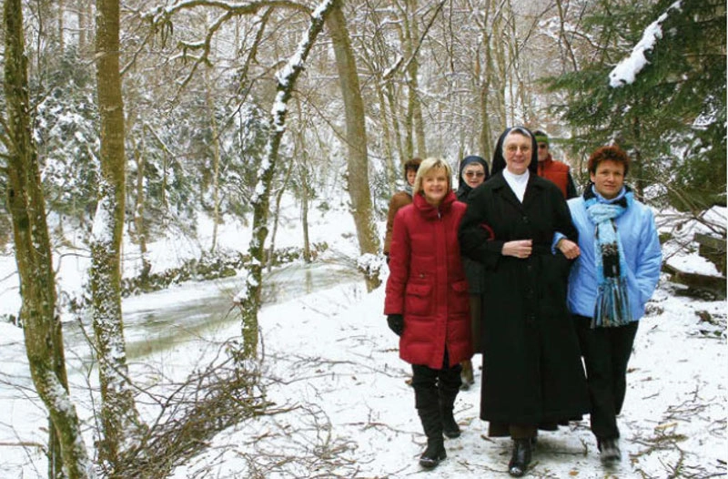 Eine Gruppe Menschen wandert mit einer Marienschwester durch den schneebedeckten Wald